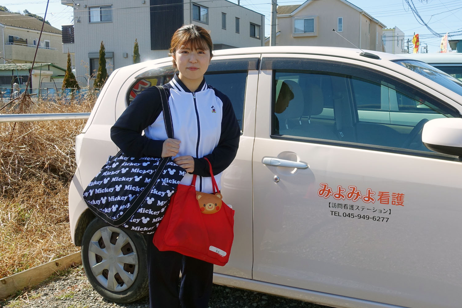 みよみよ看護の社用車の前に立つ看護師