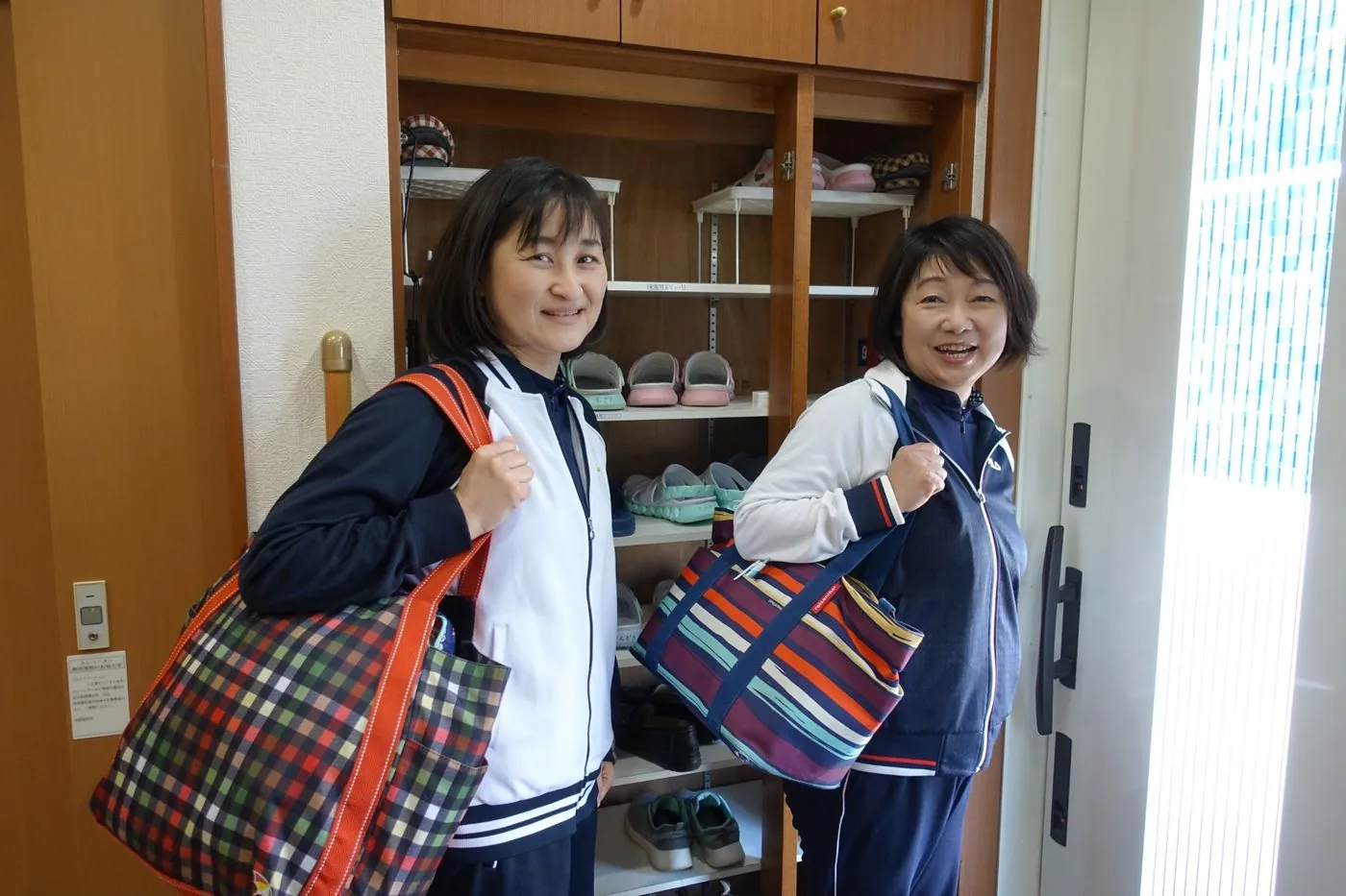訪問バッグを肩に笑顔で出発する看護師2名