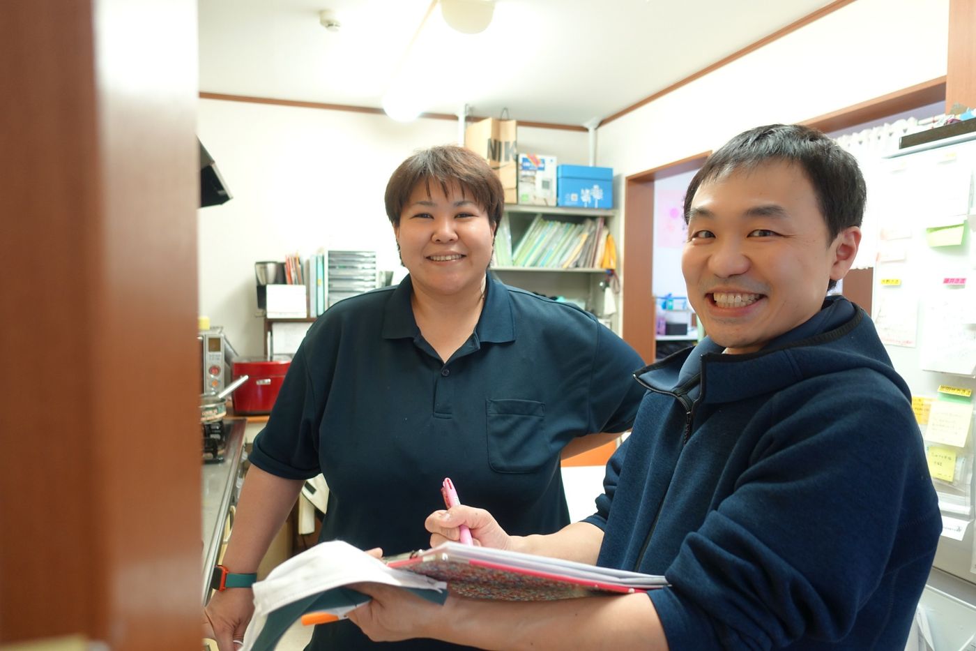 事務所で資料を手に打ち合わせをする職員2名