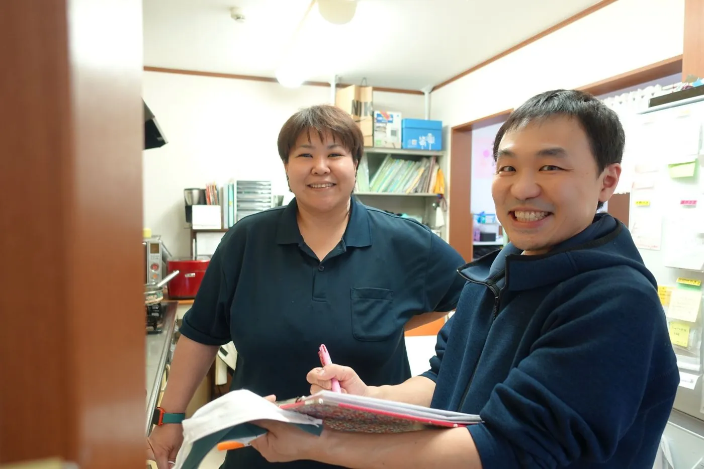 事務所で資料を手に打ち合わせをする職員2名